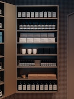 A well-organized shelf displaying a variety of products, including bottles and boxes, neatly arranged. The products appear to be skincare or personal care items, and the packaging is minimalist with neutral tones. Ceramic cups are also visible among the items on the shelf, adding a touch of elegance.
