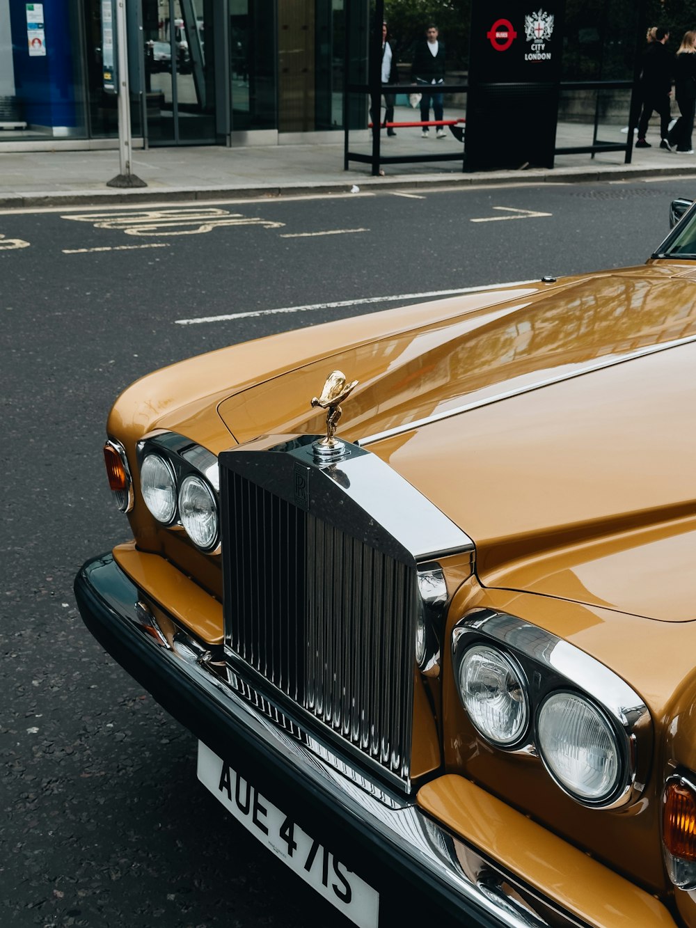 a yellow rolls royce parked on the side of the road