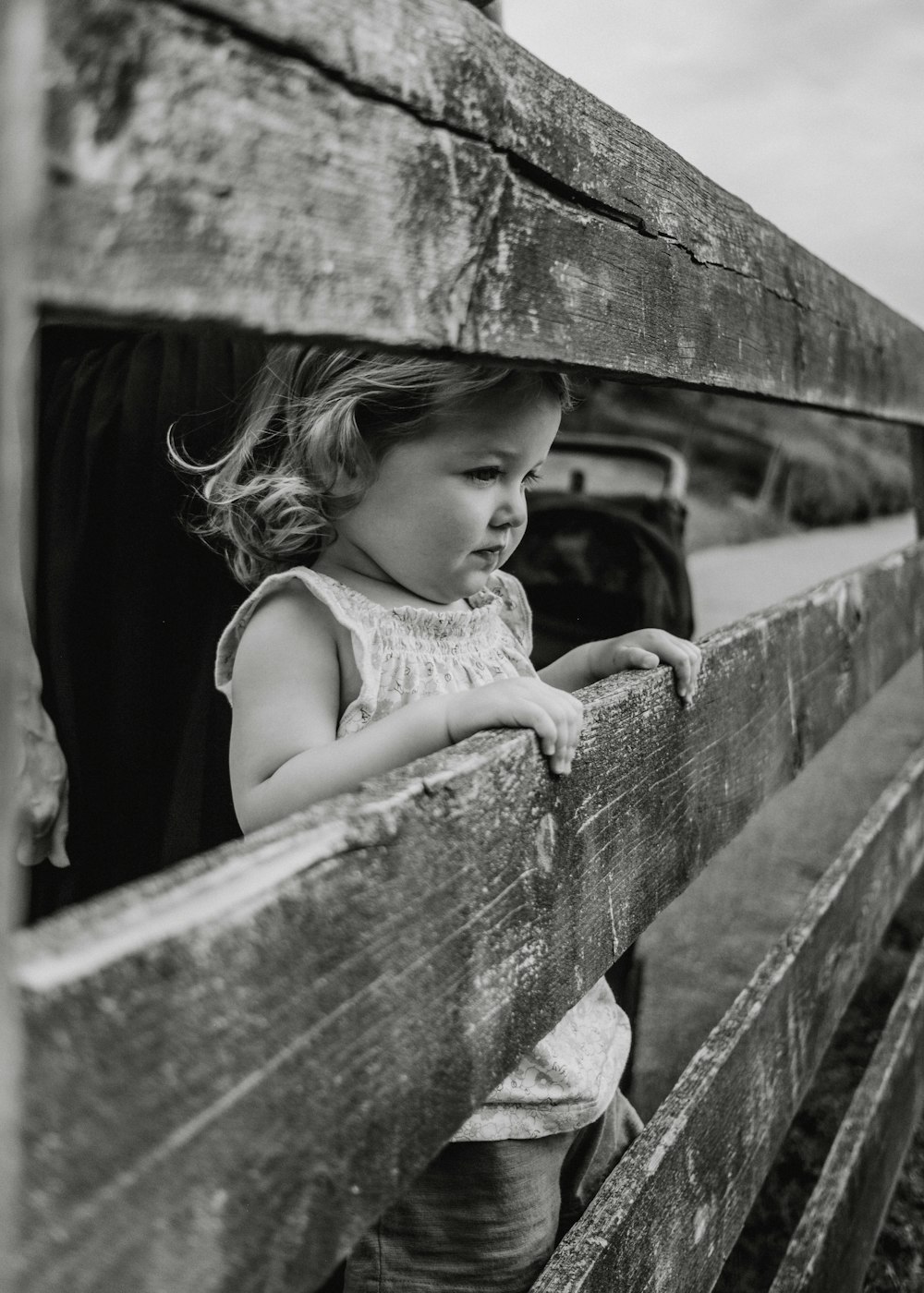 a little girl looking out of a wooden fence