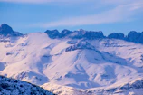 A peaceful mountain scene with snow-capped peaks and a clear blue sky.