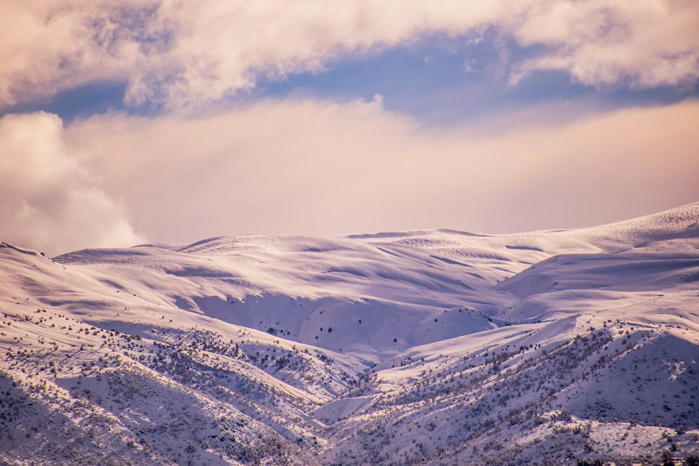 a mountain covered in snow under a cloudy sky