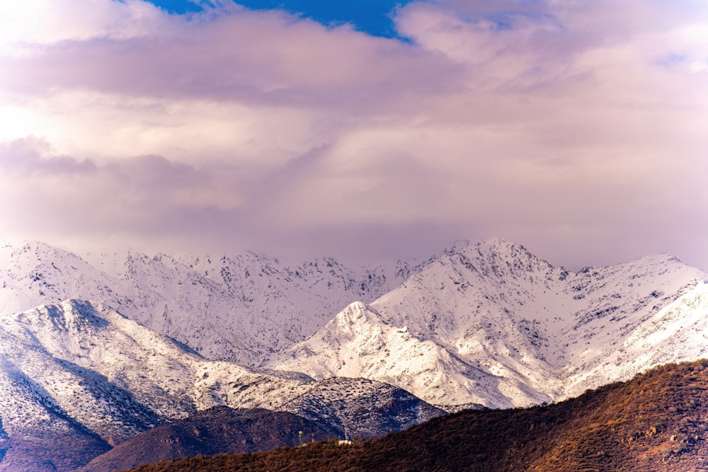 a snow covered mountain range under a cloudy sky