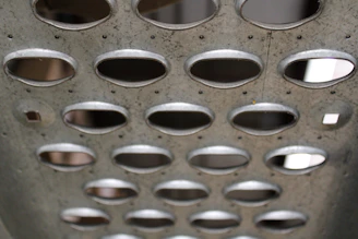 Close-up of perforated steel sheet used in coffee dryer production, highlighting precise holes and clean edges.