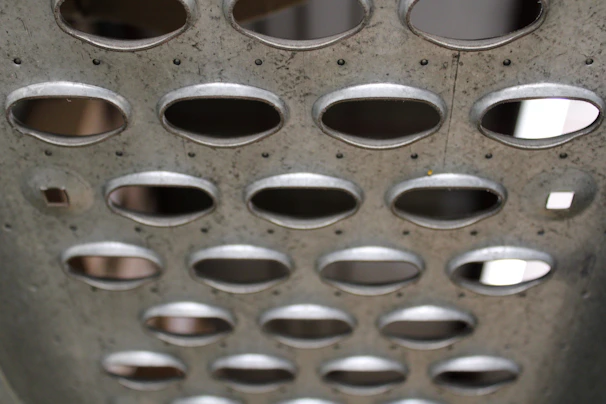 Close-up of perforated steel sheet used in coffee dryer production, highlighting precise holes and clean edges.