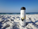 a water bottle sitting on top of a sandy beach