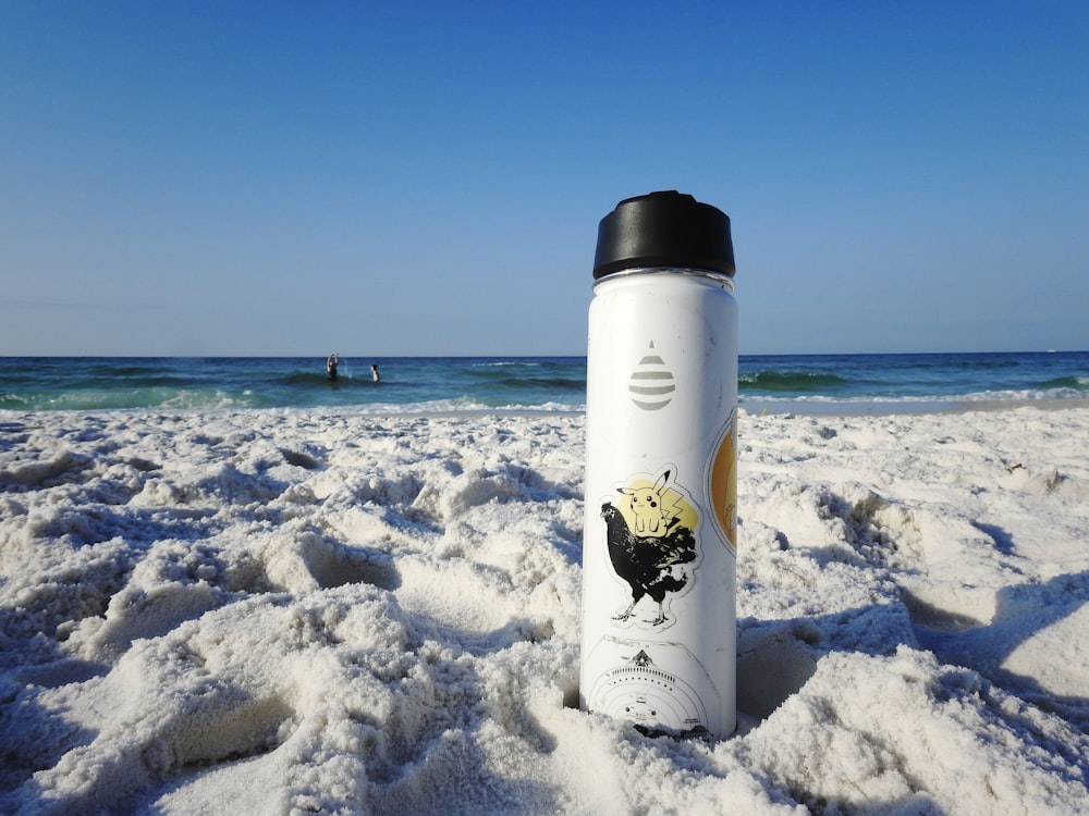 a water bottle sitting on top of a sandy beach