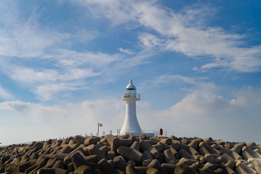 a large white lighthouse sitting on top of a pile of rocks