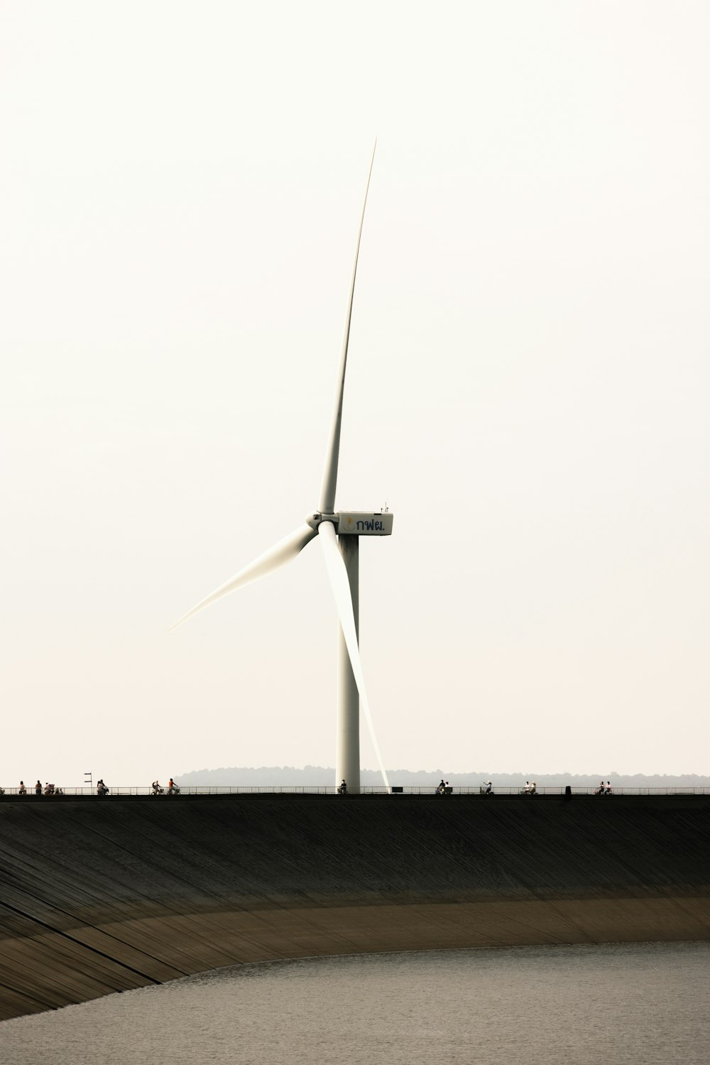 una turbina eolica sulla cima di una collina accanto a uno specchio d'acqua