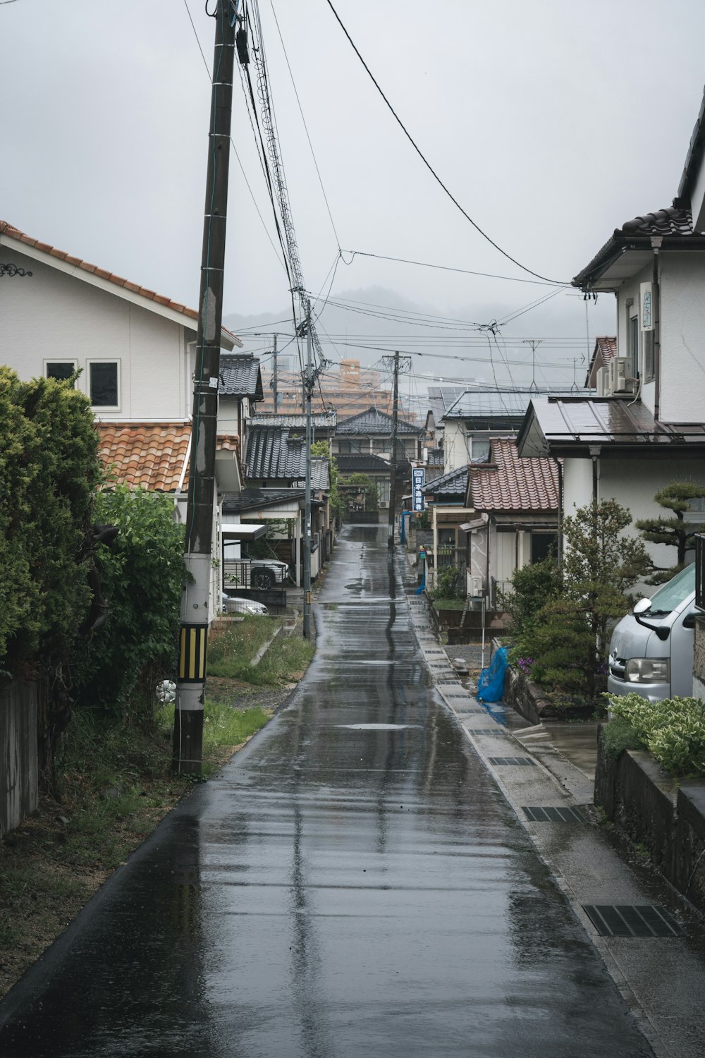 Una strada bagnata con case e linee elettriche