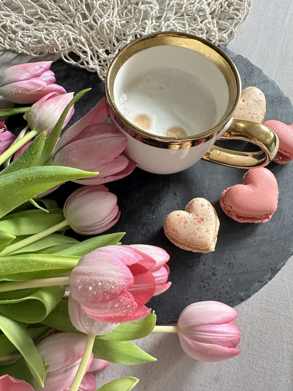a cup of coffee next to some pink tulips