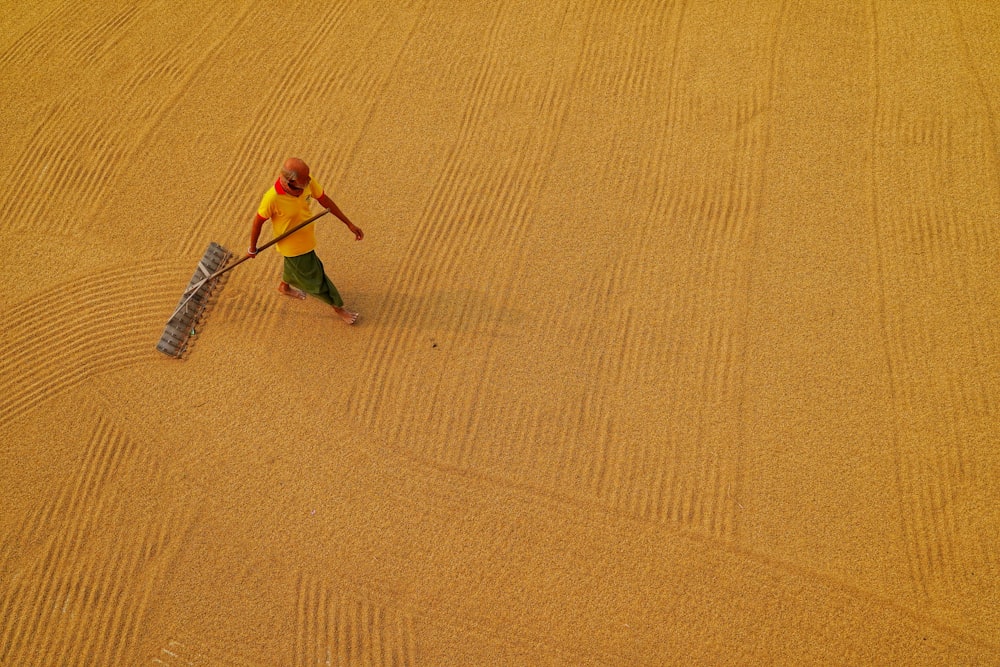 a person in a yellow shirt with a shovel in the sand