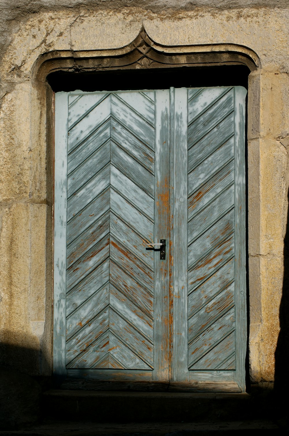 a wooden door with a metal handle on a stone building
