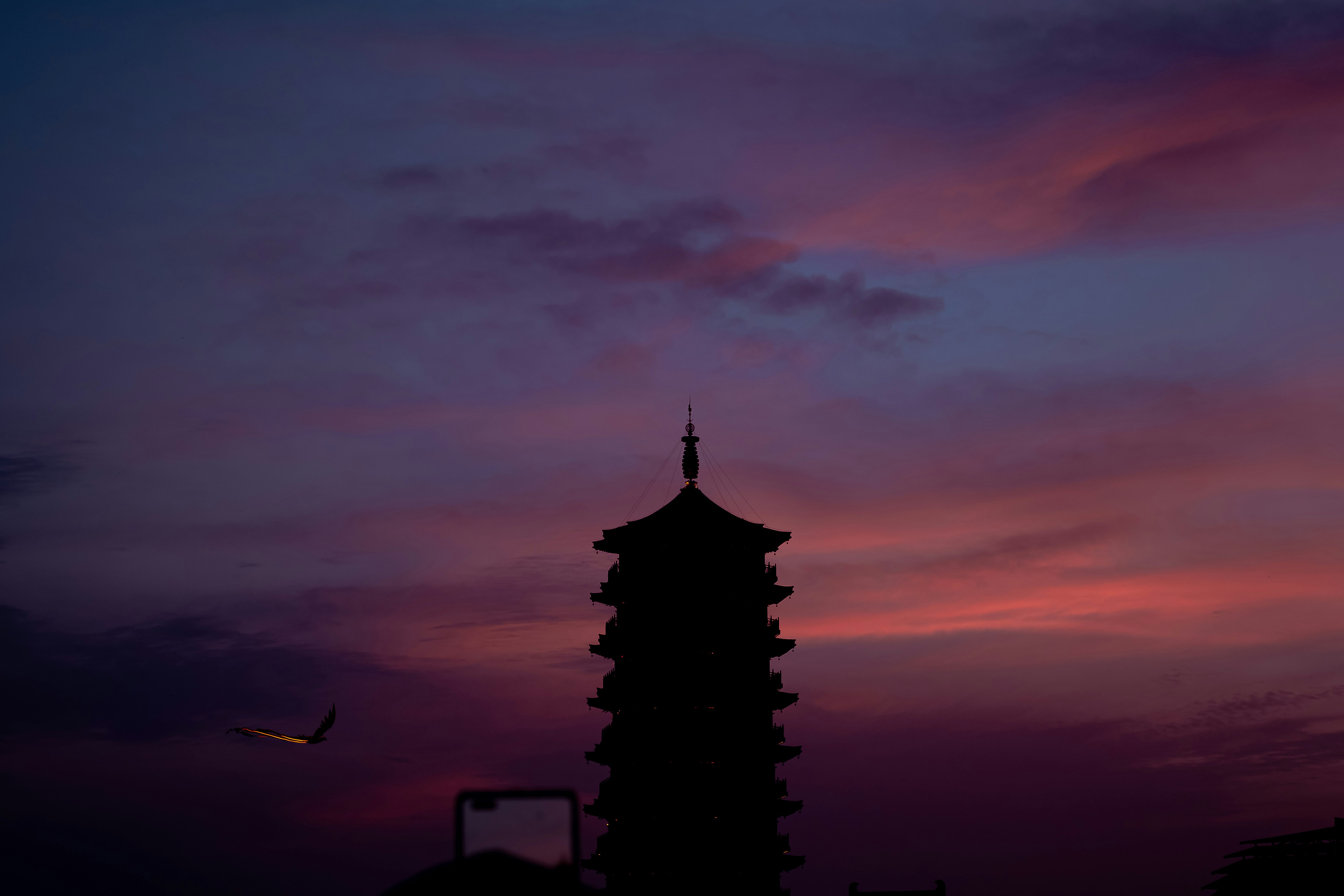 Stone pagoda silhouetted against a glowing field sunset