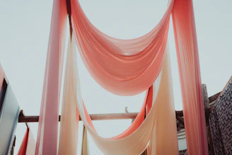 Close-up of elegant outdoor curtains fluttering softly in a warm breeze beside a gazebo canopy.