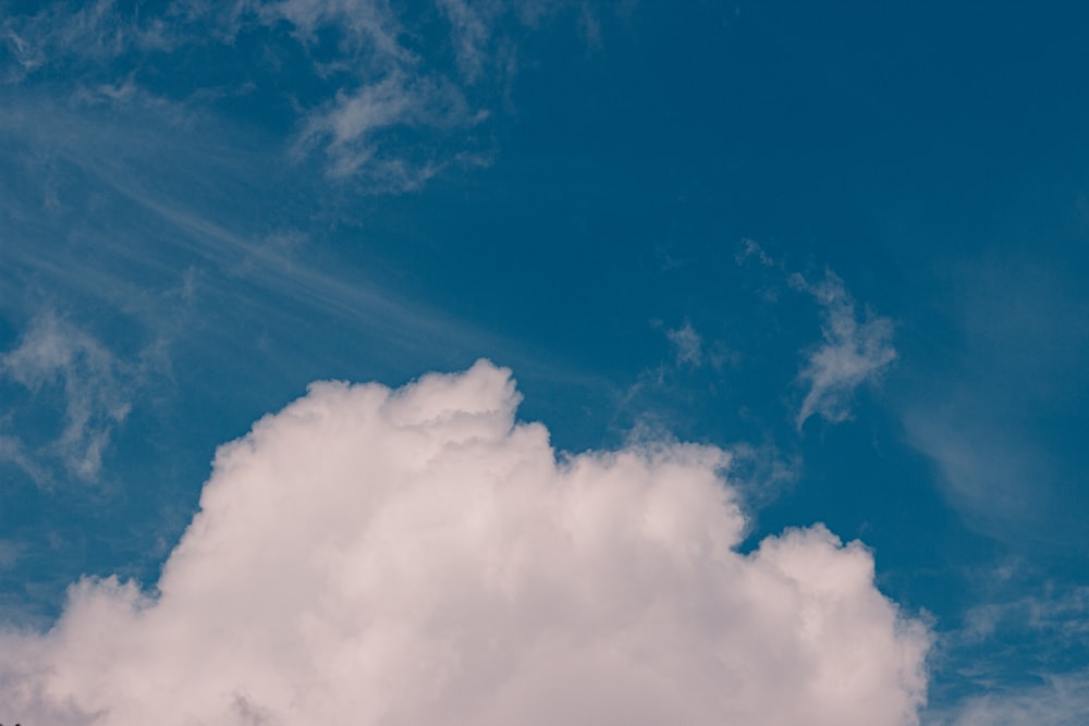 a plane flying through a cloudy blue sky