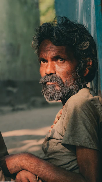 Tony standing against a weathered adobe wall, his white beard catching the warm desert light, eyes steady and voice ready to tell a story.