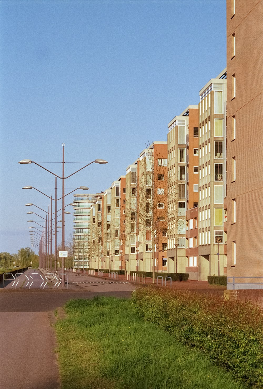 a street lined with tall buildings next to a lush green field