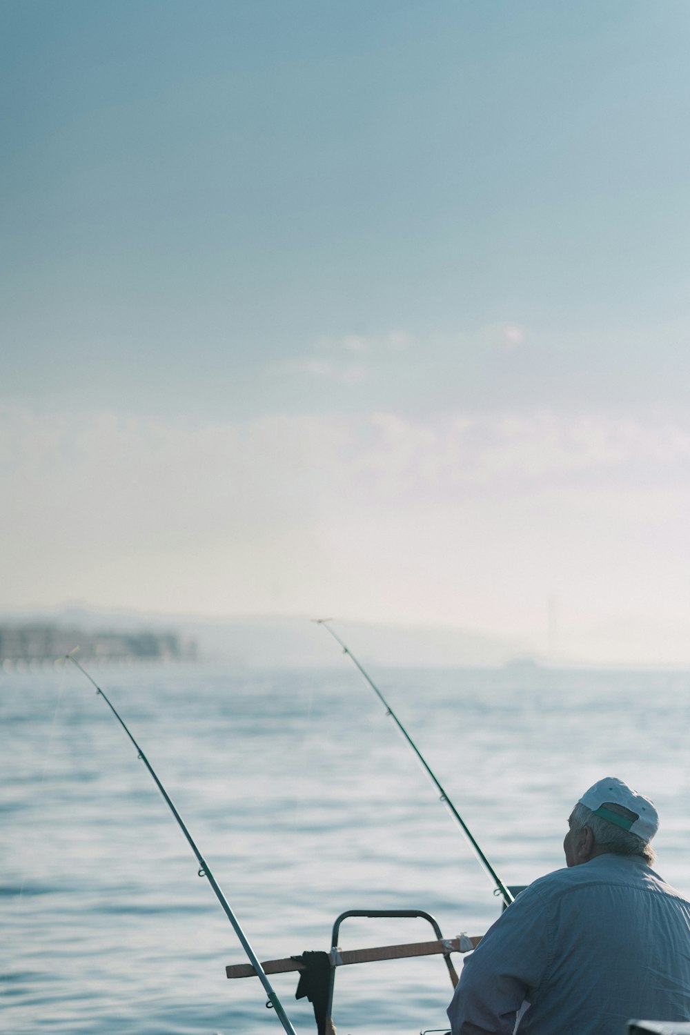 a man sitting on a boat holding two fishing rods