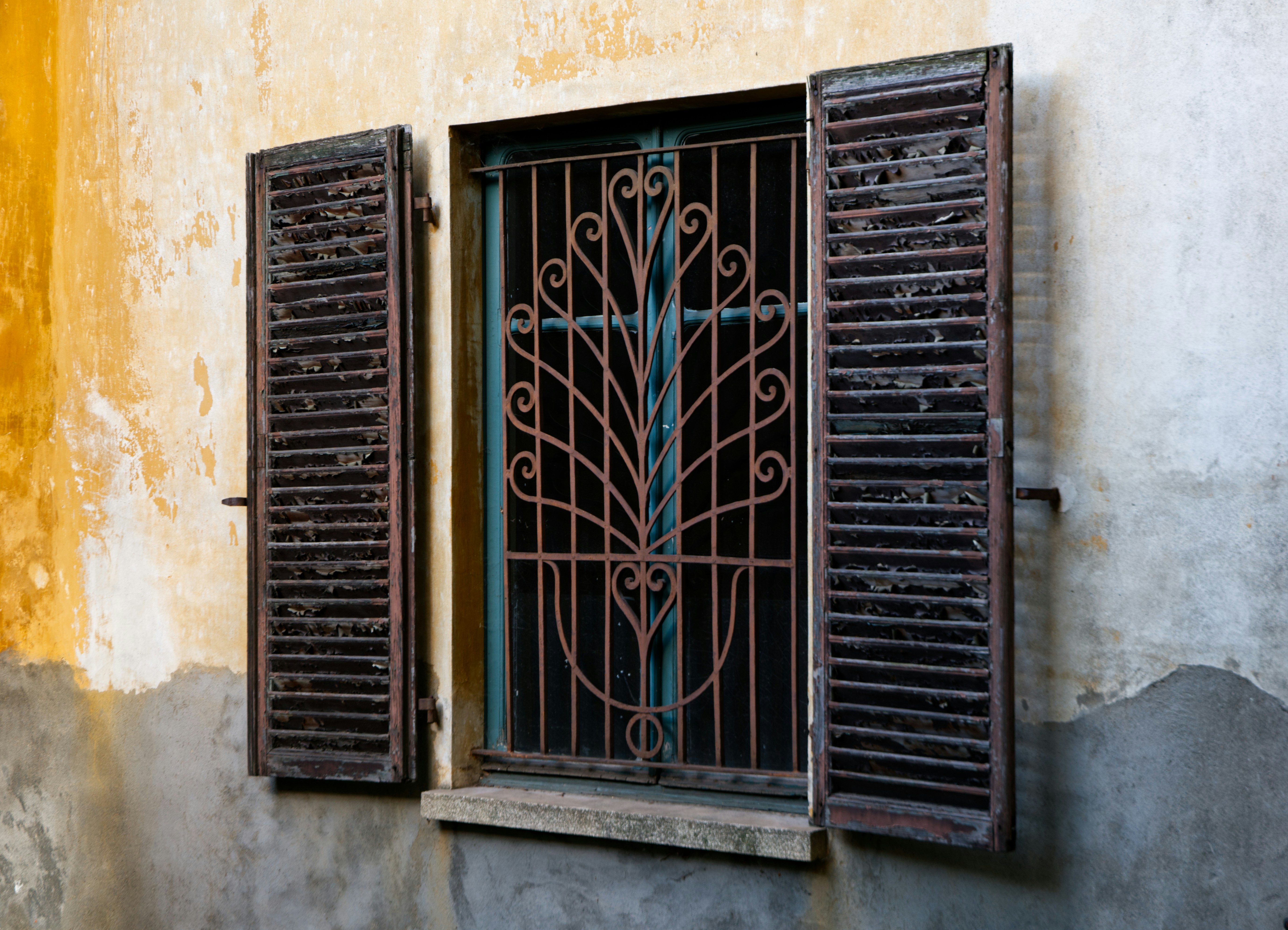 a window with a wrought iron design on the side of a building