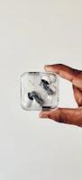 Hands holding wireless earbuds against a minimalist background