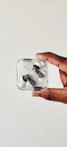 Hands holding wireless earbuds against a minimalist background