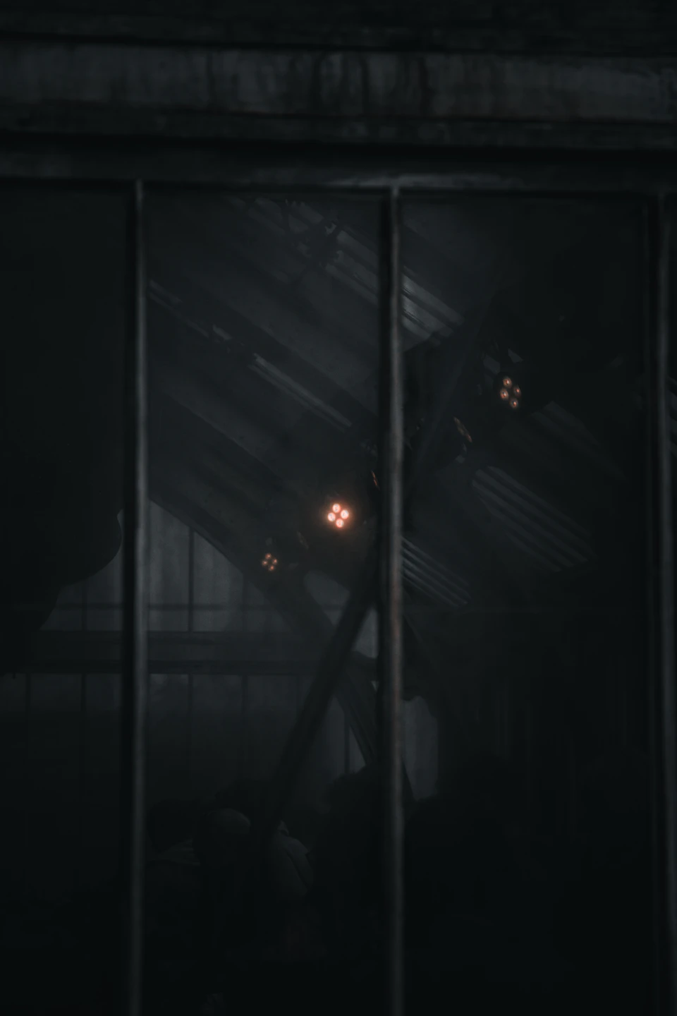 Window with three lights inside casting an ethereal glow on dark interior space