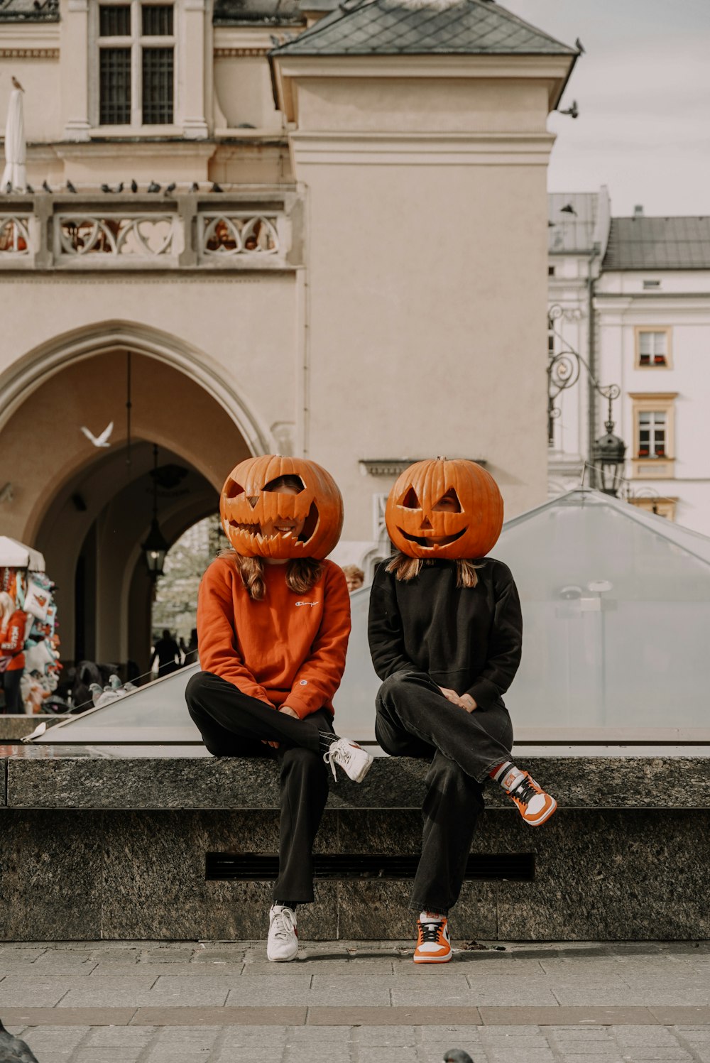 two people wearing pumpkin heads sitting on a bench