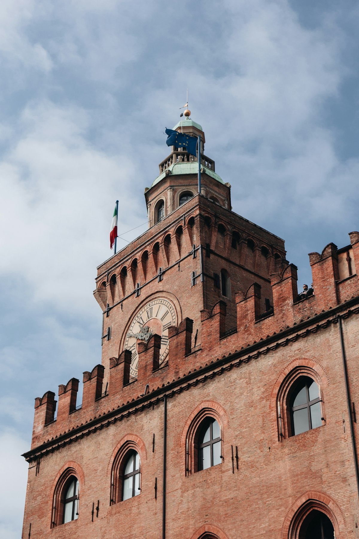 Bologna October — Palazzo Comunale clock tower above the red terracotta rooftops in autumn