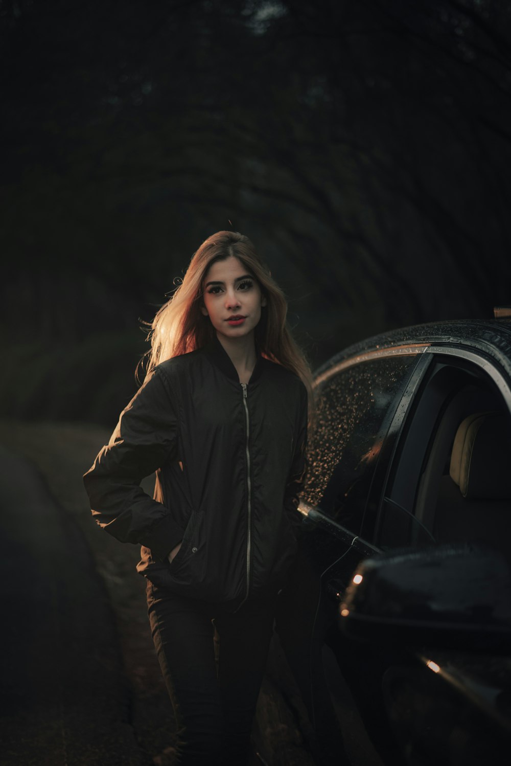 a woman standing next to a car in the dark