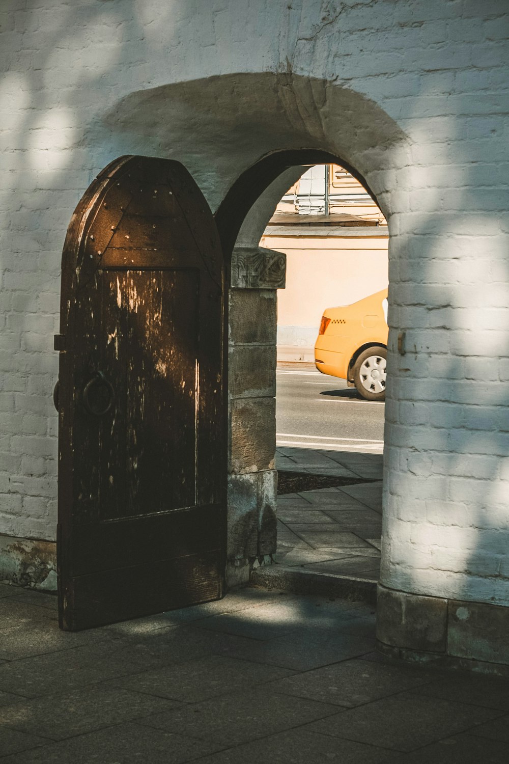 an arched doorway with a car parked in the background