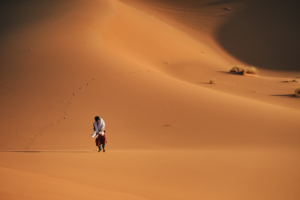 um homem caminhando por um campo de areia no deserto