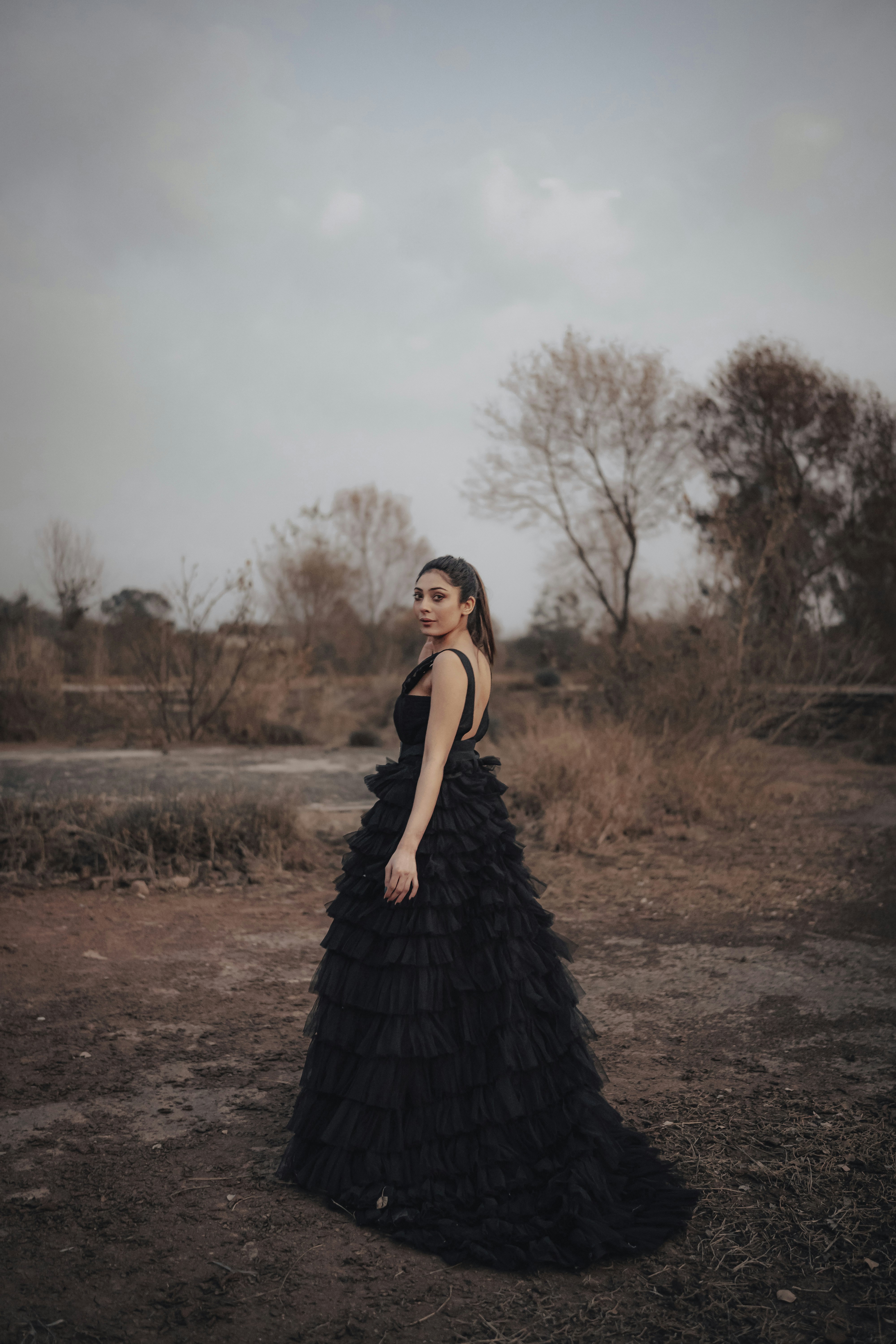 a woman in a black dress standing in a field