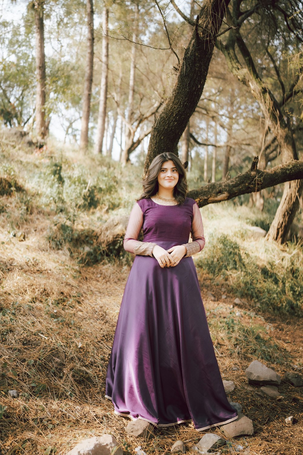 a woman in a purple dress standing in the woods