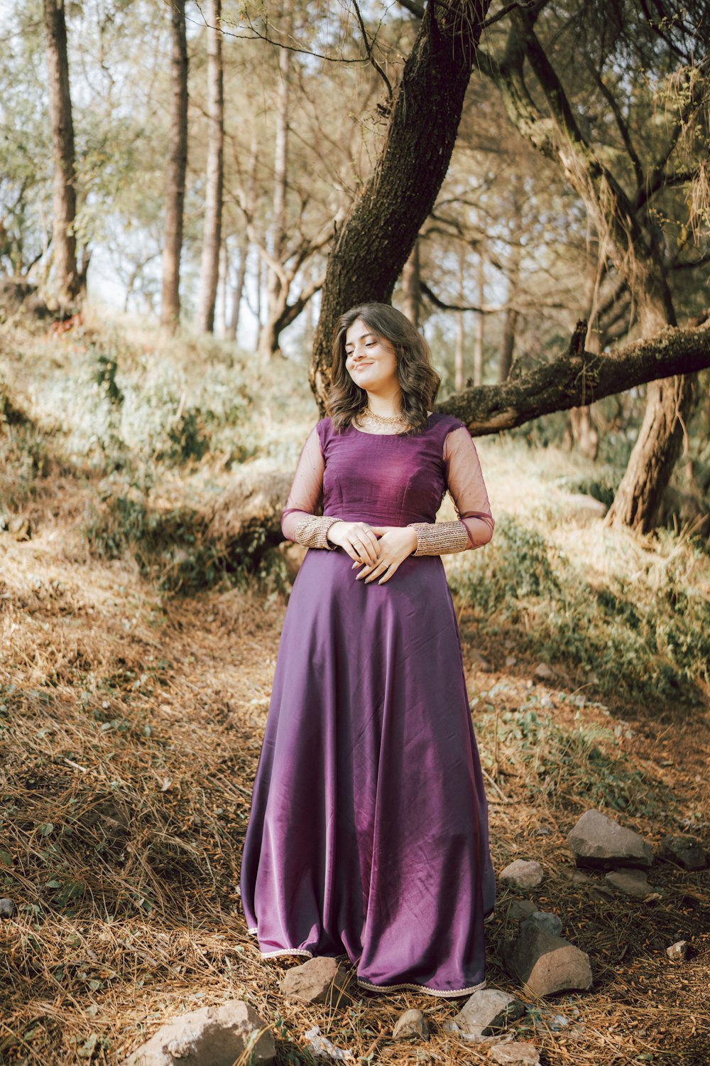 a woman in a purple dress standing in the woods