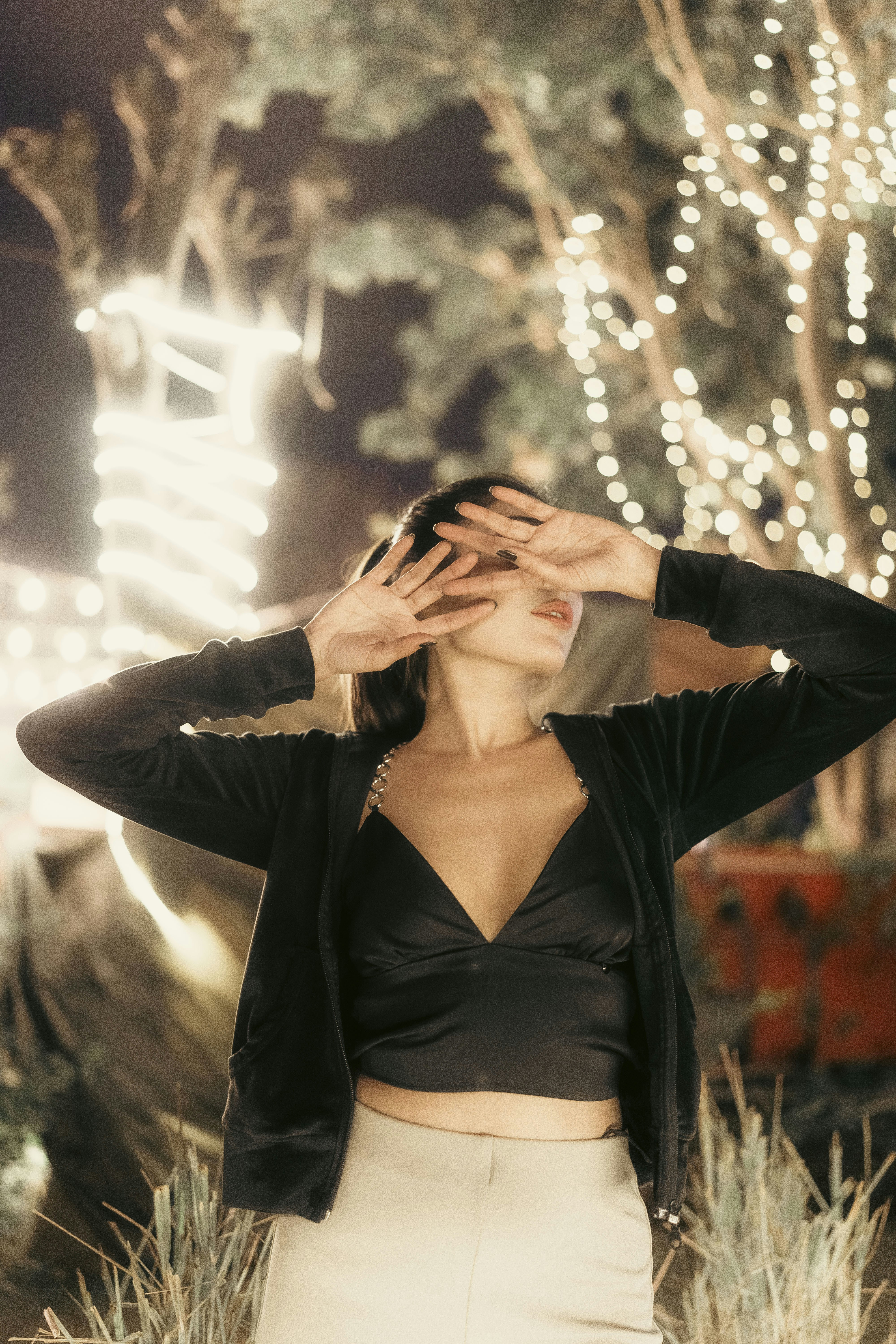 a woman standing in a field with her hands on her head
