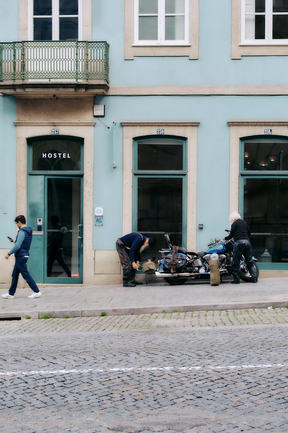 a man walking past a motorcycle parked in front of a building