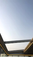 Modern residential glass roof with sleek metal structure under clear sky.