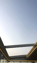 Modern glass roof covering a bright outdoor patio with sleek metal structure.