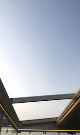 Modern glass roof covering a bright outdoor patio with sleek metal structure.