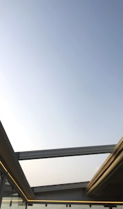 Photo of a sleek steel and glass rooftop cabin with a modern design under clear blue sky.