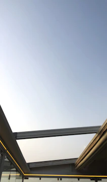 Modern residential glass roof with sleek metal structure under clear sky.