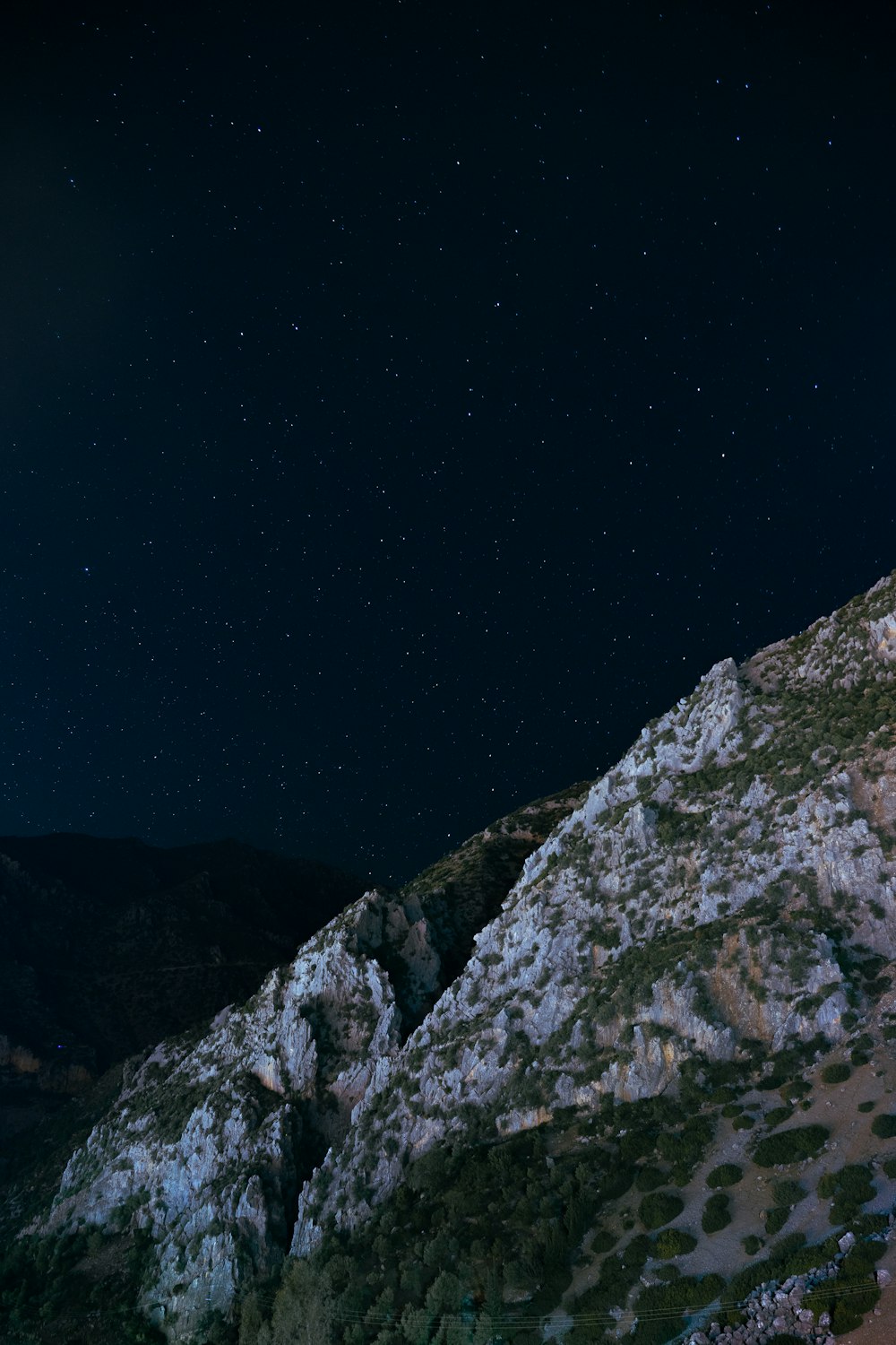 the night sky is full of stars above a rocky mountain