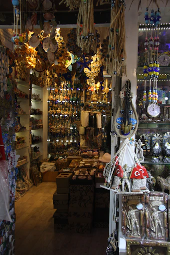 A vibrant display of colorful Indian crockery arranged on wooden shelves inside Goodluck Crockery shop.