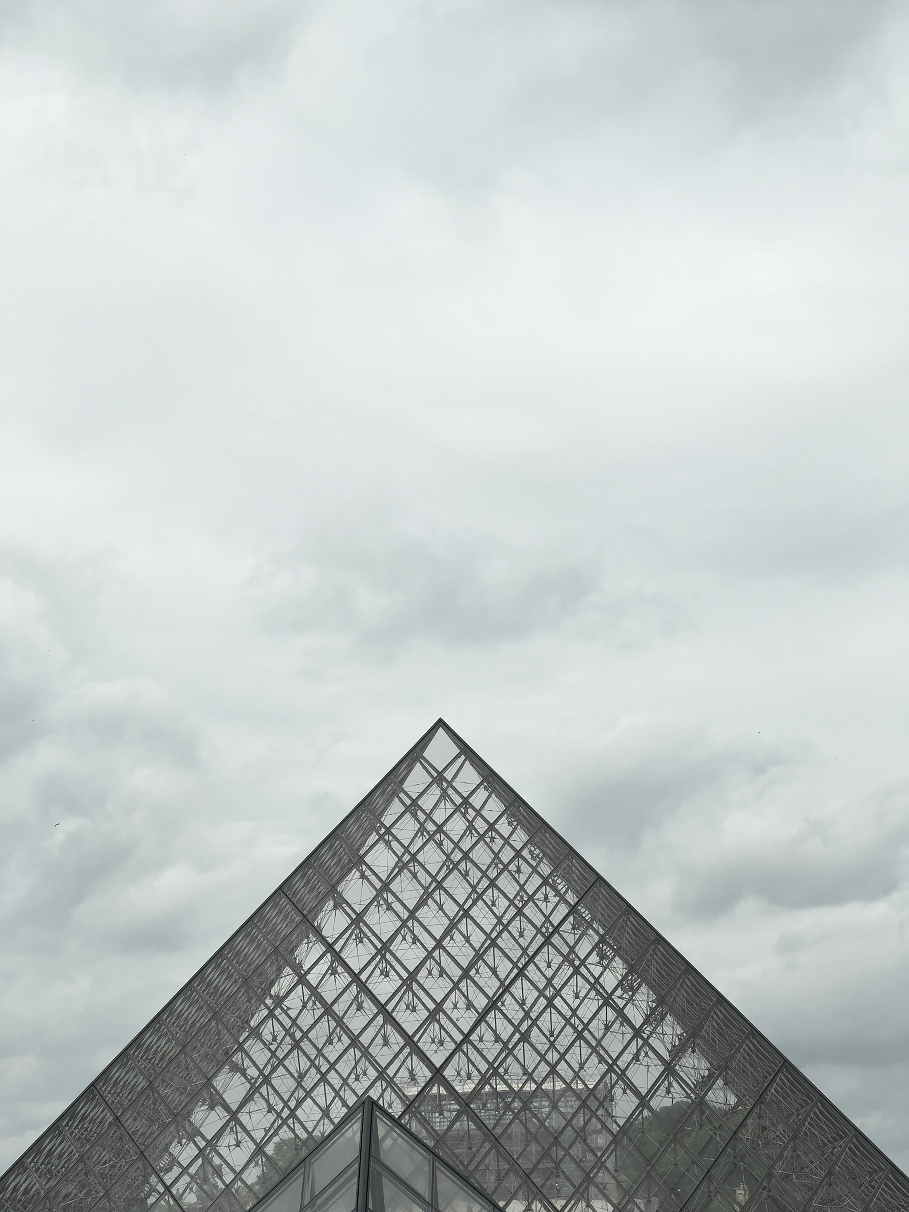 a very tall glass pyramid with a sky background