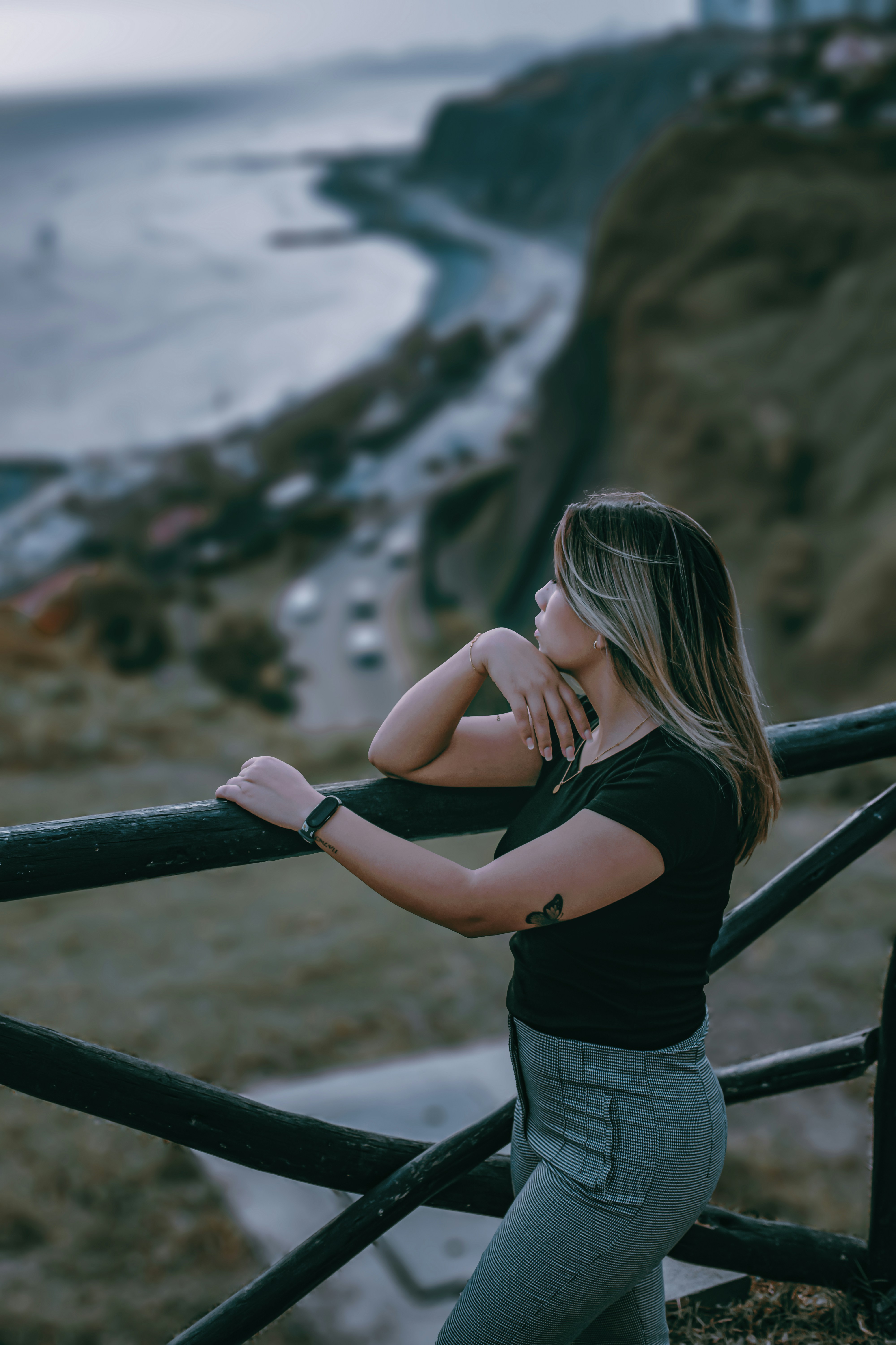 a woman leaning on a railing looking at the ocean