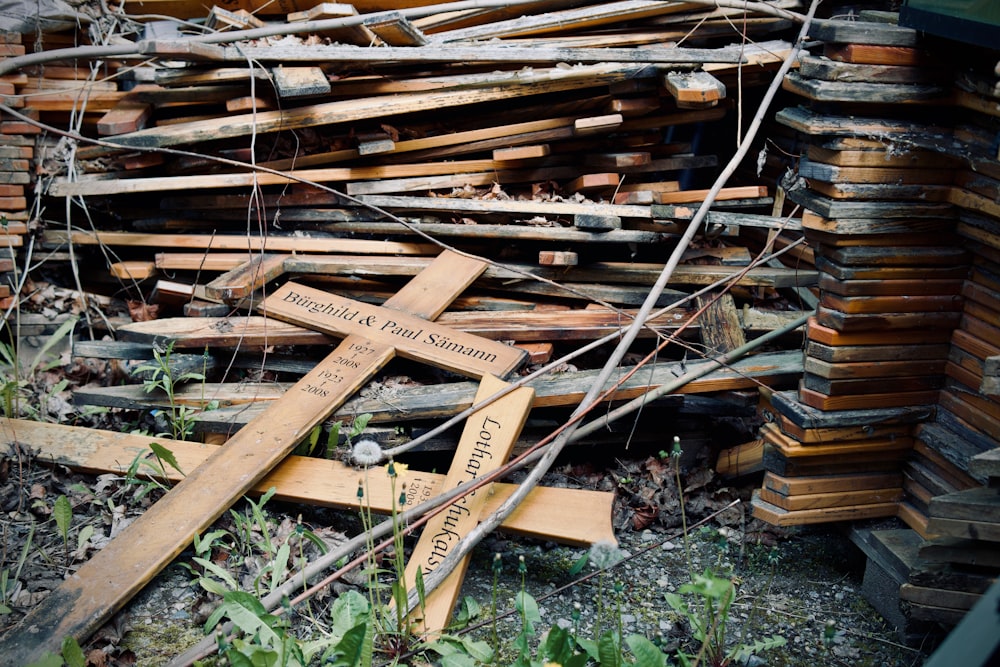 a cross laying on the ground in front of a pile of wood