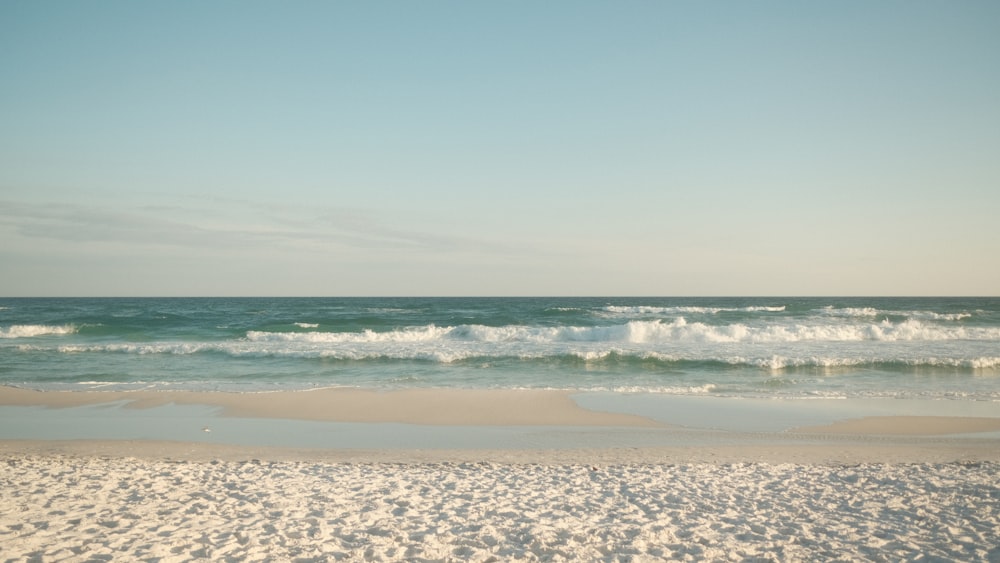 a sandy beach with waves coming in to shore