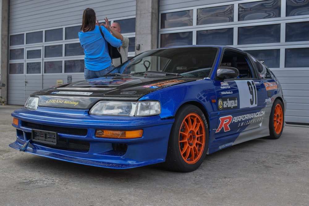 a couple of people standing on top of a blue car