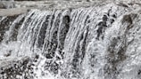 Close-up of water droplets splashing as a waterfall crashes into a rocky pool.