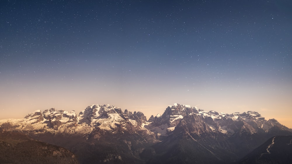 a view of a mountain range at night with stars in the sky